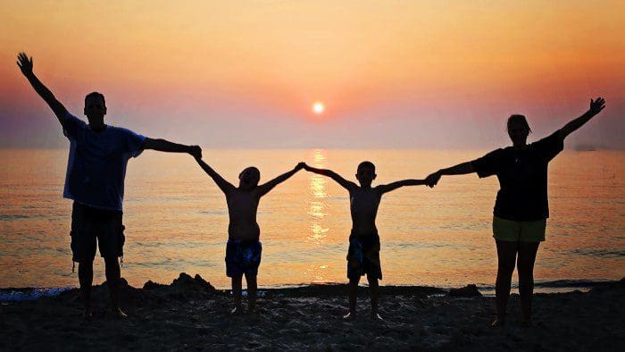 family holding hands during sunset on beach