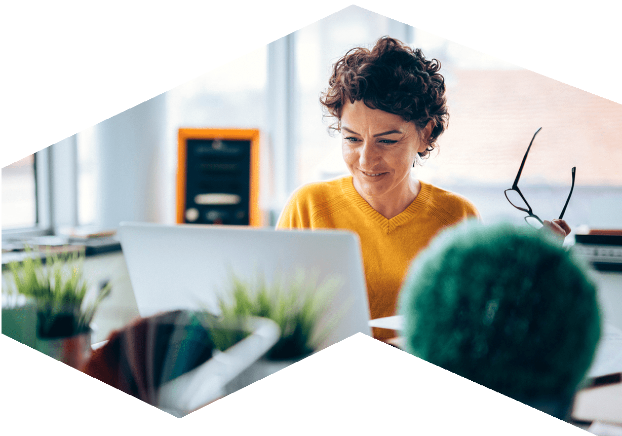 Woman working at her laptop and smiling, in a casual setting.